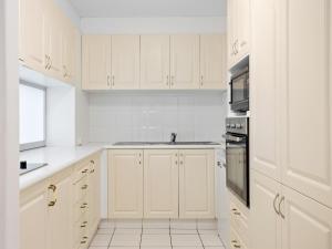 una cocina blanca con armarios blancos y fregadero en Condor Apartments by Gold Coast Premium en Gold Coast