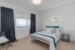 a white bedroom with a bed and a window at Charming 1920s Villa on Bealey Ave in Christchurch