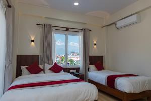 two beds in a hotel room with a window at Hotel Sandalwood in Pokhara