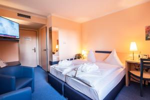 a hotel room with a bed and a desk and a television at Hotel am Tierpark Gotha in Gotha