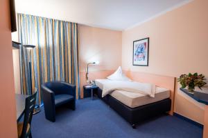 a hotel room with a bed and a chair at Hotel am Tierpark Gotha in Gotha