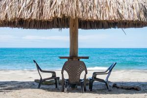two chairs sitting under an umbrella on the beach at UUTTAAKA Eco-Hotel in Palomino