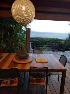 una mesa de madera y sillas en una terraza con vistas al océano en CHAMBRE CHEZ L HABITANT PISCINE VUE MER SDB et TERRASSE PRIVEE, en Saint-Pierre