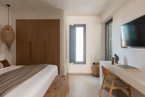 a bedroom with a bed and a desk and a television at Phos Milos in Pollonia