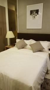a large bed with white sheets and pillows at One Tebrau by Iconic Bliss in Johor Bahru