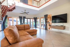 un soggiorno con divano e TV a schermo piatto di Beautiful 5BR Villa Felicity, Pool & Garden, near Naiharn a Rawai Beach