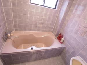 a bath tub in a tiled bathroom with a toilet at SKYROAD Adult Only in Tokyo