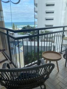 a balcony with a bench and a table and the ocean at Fabulous Sea Views in the heart of Surfers in Gold Coast
