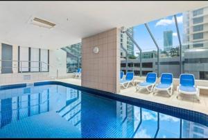 a swimming pool with blue chairs in a building at Fabulous Sea Views in the heart of Surfers in Gold Coast