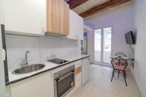a kitchen with white cabinets and a sink and a table at JBO- Joette's Bliss Oasis in Valletta