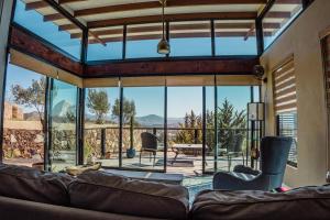 un soggiorno con divano e una grande finestra in vetro di Rancho Cien Piedras a Valle de Guadalupe