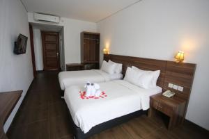 a hotel room with a bed with a stuffed dog on it at Azza Hotel Palembang in Palembang +4 photos