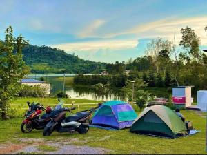 een groep tenten en motorfietsen geparkeerd naast een meer bij เขาเจ้าขา2 in Khao Kho