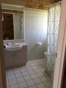 a bathroom with a sink and a shower with a mirror at Boulder Opal Motor Inn in Winton