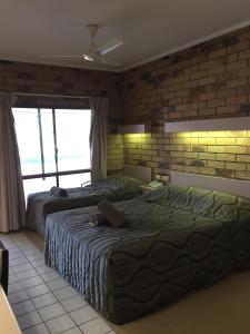 a bedroom with two beds and a brick wall at Boulder Opal Motor Inn in Winton