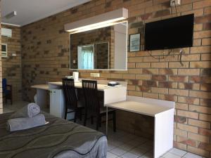 a room with a desk and a tv on a brick wall at Boulder Opal Motor Inn in Winton