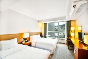 a hotel room with two beds and a window at Bareve Hotel in Seogwipo