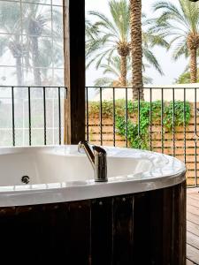 a bath tub in front of a window with palm trees at Crimson View in Moshav Ramot