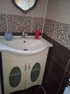ein Badezimmer mit einem weißen Waschbecken und einem Spiegel in der Unterkunft Апартаменты PAROSTKI in Swaljawa