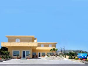 a large yellow building with palm trees in front of it at Zefiro Residence in Siderno Marina