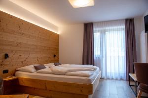 a bedroom with a large bed with a wooden wall at Garni Siebnerhof in San Candido