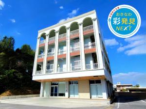 un edificio blanco con un cartel que dice en Villa Blu Okinawa Chatan 3-3 ヴィラブルー沖縄北谷3-3 "沖縄アリーナ徒歩圏内の民泊ホテル", en Chatan