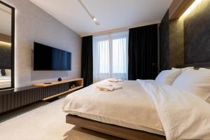 a bedroom with a large bed and a flat screen tv at Aparthotel Woodside by Anaya in Kopaonik