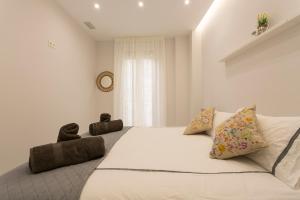 a white bedroom with a large bed and a window at Apartamento San Isidro Centro in Granada