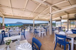 a restaurant with white tables and blue chairs at Kiani Beach Resort Family All Inclusive in Kalyves