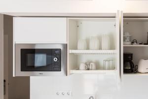 a microwave in a kitchen with white cabinets at Loft Matilde by Grupo Matilde in Las Palmas de Gran Canaria +14 photos