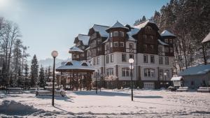 a large building in the snow with snow on the ground at Wellness Penzión Smerdžonka - KÚPELE PIENINY in Červený Kláštor