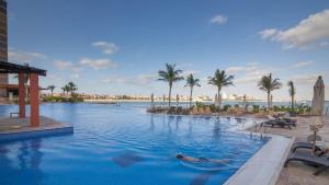 een zwembad in een resort met palmbomen en een waterlichaam bij Tiara · Luxury Palm Jumeirah · Private Beach and Pool! in Dubai