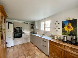 a kitchen with white appliances and a sunflower painting on the wall at Maison de famille près de la mer in Bénodet