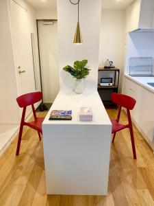 a kitchen with two red chairs and a white counter at Ken's Place四谷 in Tokyo