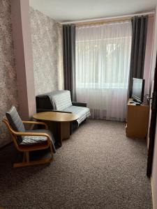 a room with a table and a couch and a window at Hotel Sudety in Głuchołazy