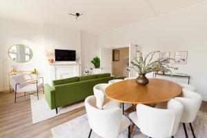 een woonkamer met een groene bank en een tafel en stoelen bij The Fulham Escape - Alluring 5BDR Flat in Londen
