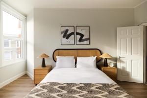 een slaapkamer met een bed met witte lakens en 2 lampen bij The Fulham Escape - Alluring 5BDR Flat in Londen