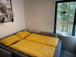 a yellow bed in a room with a window at Golte Apartment Tibona in Mozirje