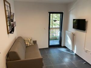 a living room with a couch and a television at Golte Apartment Tibona in Mozirje