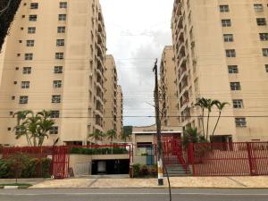 dos edificios altos con una valla roja al lado de una calle en Apartamento Enseada, en Guarujá