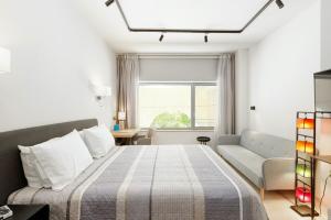 a bedroom with a bed and a couch and a window at Square Elegant Suites in Thessaloniki