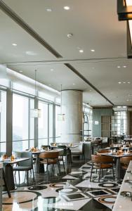 a dining room with tables and chairs and windows at Pullman Shenzhen North in Shenzhen