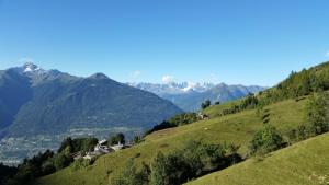 a village on a hill with mountains in the background at Agriturismo Stella Orobica in Albosaggia