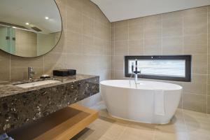 a bathroom with a tub and a sink and a mirror at Hundert Hills in Jeju