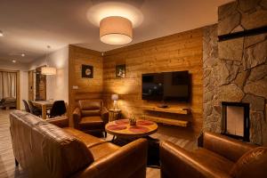 a living room with leather furniture and a stone wall at Apartmán Polana in Demanovska Dolina