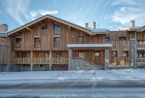 ein großes Holzgebäude mit Schnee auf dem Boden in der Unterkunft Appartement Panorama, résidence Les Alpages in Montvalezan