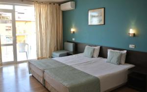 a bedroom with a large bed with a blue wall at Valeo Hotel in Balchik