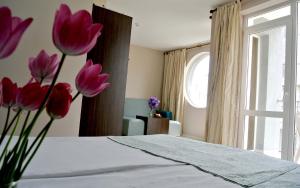 a room with a bed with pink flowers on it at Valeo Hotel in Balchik