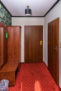 a room with two wooden doors and a red carpet at Hotel Stara Gorzelnia in Licheń Stary
