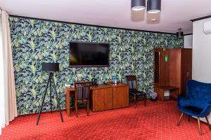a room with a tv and a desk and chairs at Hotel Stara Gorzelnia in Licheń Stary